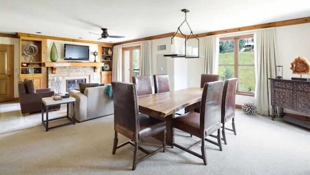 Amplia sala de estar con comedor, chimenea y un ventanal con vistas al exterior.