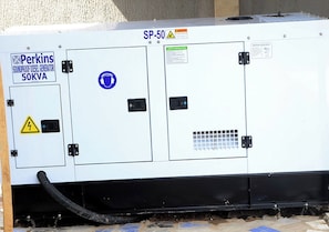 Ein Perkins-Schalldämmgenerator mit Dieselantrieb, 50 KVA, mit Warnhinweisen und angeschlossenem Schlauch.