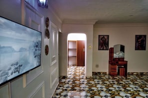 Un pasillo con piso estampado, un televisor de pantalla plana, un aparador de madera y una puerta que da a otra habitación.