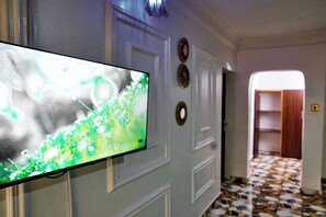 A hallway with a television mounted on the wall, a patterned floor, and a door leading to another room. - contemporary Apartrment with a distinct African flare. (Ibadan)