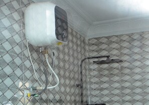Ein Badezimmer mit Fliesenboden, einer Dusche und einem weißen Heizgerät an der Wand.
