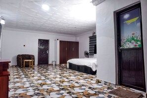 A room with a bed, a chair, a wardrobe, and a fan. - contemporary Apartrment with a distinct African flare. (Ibadan)