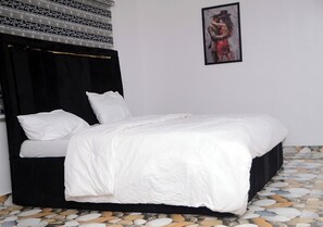 Ein Bett mit weißer Bettwäsche, einem schwarzen Kopfteil und einem gerahmten Bild an der Wand.