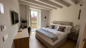 Ein Schlafzimmer mit Bett, Nachttischen, einem Fernseher und Blick auf ein Gebäude.