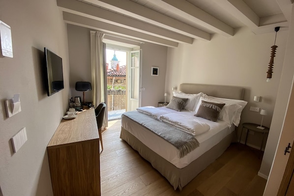 A bedroom with a bed, bedside tables, a TV, and a view of a building outside.