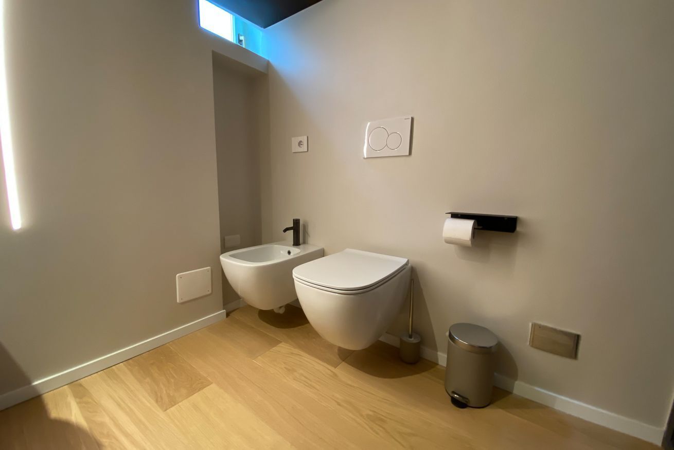 Ein modernes Badezimmer mit einer Bidet, Toilette und einem Mülleimer.