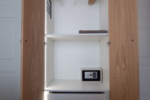 A room with a white door, a wooden cabinet, and a small safe on the lower shelf.