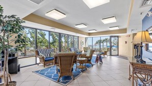 Un amplio vestíbulo con muebles de mimbre, ventanas grandes y vistas a palmeras.