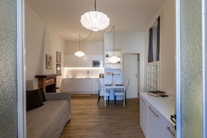 A modern interior with a sofa, dining table, chairs, and a kitchen area.