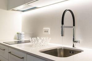 A modern kitchen with a stainless steel sink, a white decorative bowl, and a sleek faucet.