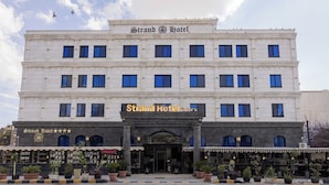 Un edificio con un letrero que dice 'Strand Hotel' y un escaparate donde se ve la palabra 'PRODUCTO'.