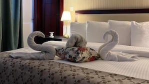 Una habitación de hotel con cama, mesita de noche, lámpara y puerta.