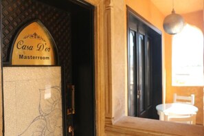 Opastekyltti, jossa lukee ”Casa D’or Masterroom”, ja sen yhteydessä ovi sekä ikkuna, jonka sisällä on tuoli.