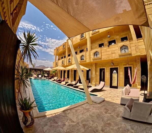 A pool area with lounge chairs, a pool, and a building with balconies. - Casa D'or  Dahab  (Dahab)