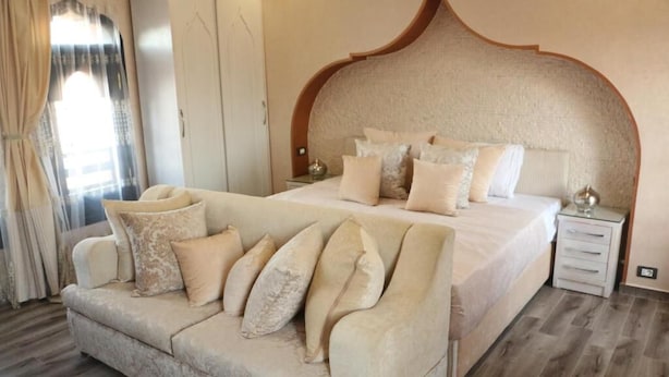 Quarto com uma cama grande, um sofá, um guarda-roupa e uma mesa de cabeceira.