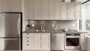 Une cuisine moderne dotée d’appareils électroménagers en acier inoxydable, d’un plan de travail en granit et de meubles de couleur claire.