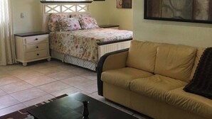 Un dormitori amb un llit, una taula de nit, un sofà i un ventilador de sostre.