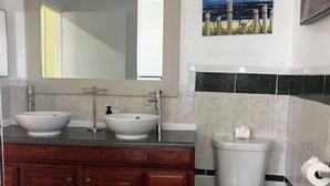 Un bany amb un lavabo, dues aixelles, un vàter i un gresol.