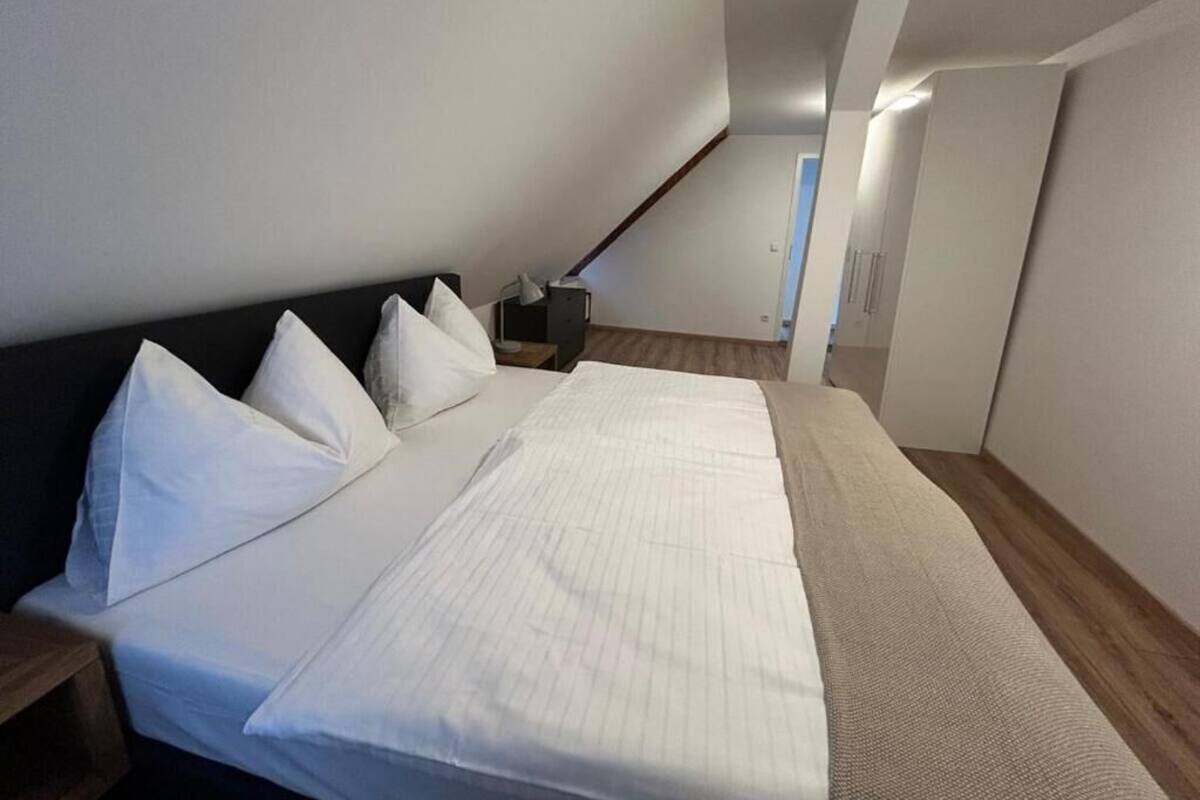 A bedroom with a bed, pillows, a bedside table, and a nightstand.