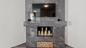 A modern fireplace with a flat-screen TV mounted above it. - Faraway Homes Studios Bruck 13 (Bruck an der Mur)