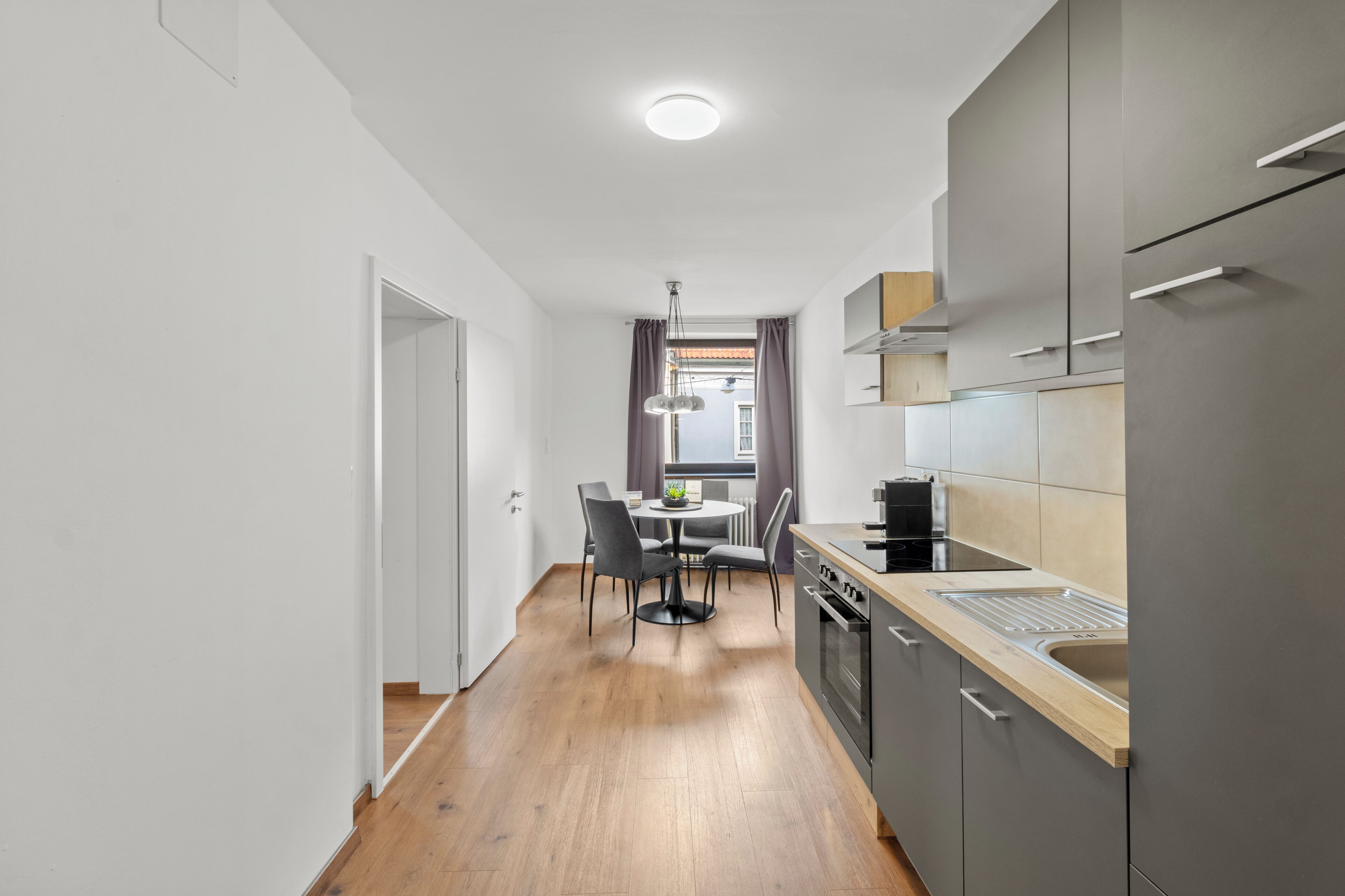 A modern kitchen with grey cabinets, a wooden countertop, and a built-in oven.