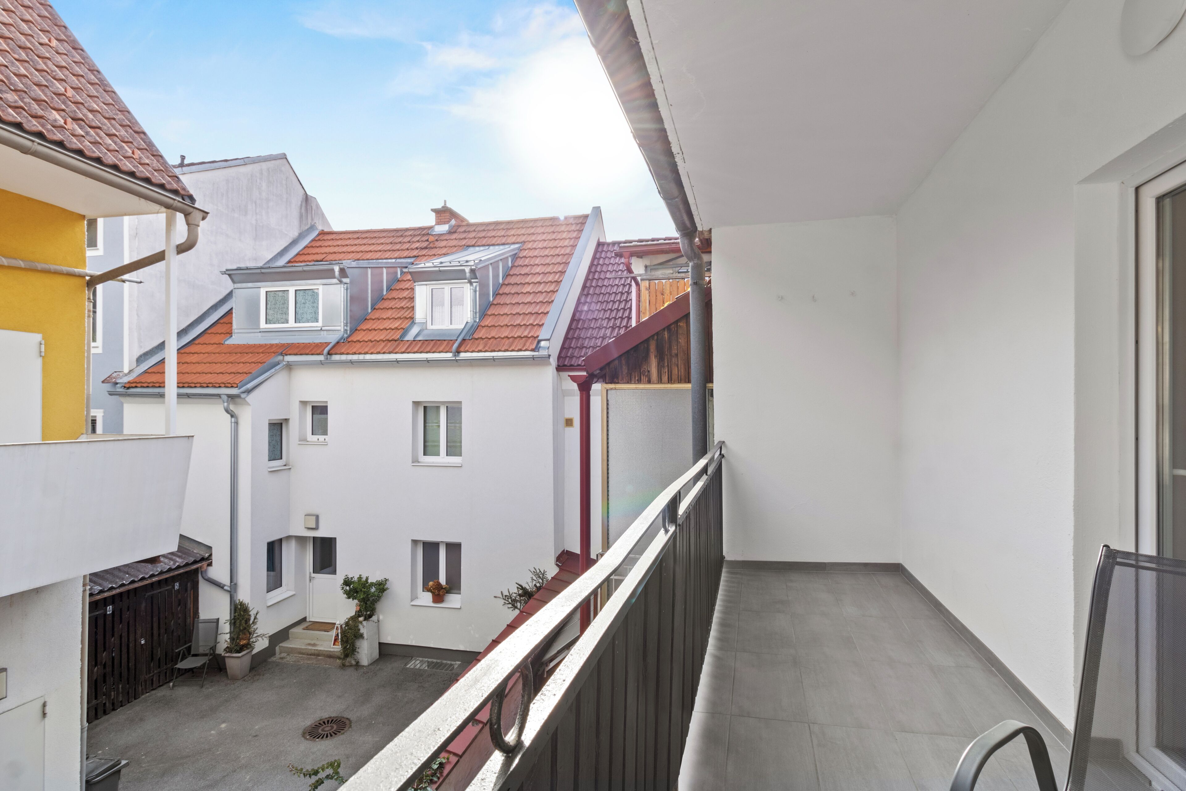 A balcony with a view of neighboring buildings, a railing, and a door.