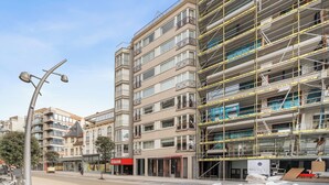 Ein mehrstöckiges Gebäude mit modernem architektonischen Design, das Balkone und große Fenster aufweist.