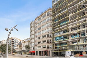 Ein mehrstöckiges Gebäude mit modernem architektonischen Design, das Balkone und große Fenster aufweist.