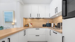 Eine moderne Küche mit weißen Schränken, einer Holz Arbeitsplatte und einer schwarzen Mikrowelle.