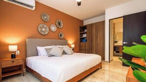 A bedroom with a bed, bedside tables, wall decor, and a wardrobe. - Ceiba 25 | Rooftop Pool, Gym & 5th Ave Condo (Playa del Carmen)