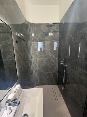 A modern bathroom with dark marble walls, a white bathtub, and a shower area. - Villa Eralion | Adults Pool · Jacuzzi · Fire Pit · En-Suites · Garden · Private (Qarku i Tiranës)