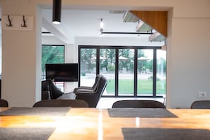 A modern living room with a sofa, a flat-screen TV, and a dining table.