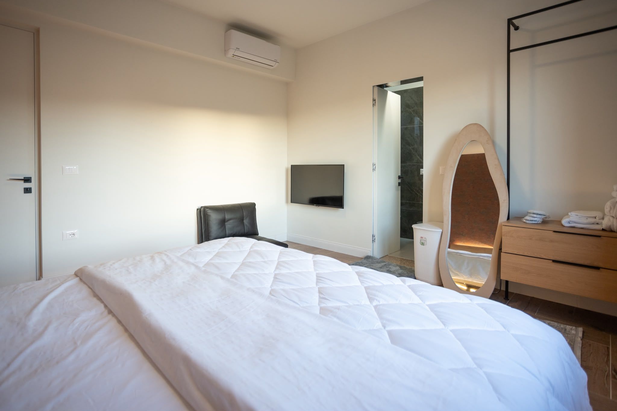 Ein Hotelzimmer mit Bett, Fernseher, Spiegel, Stuhl und Kommode.