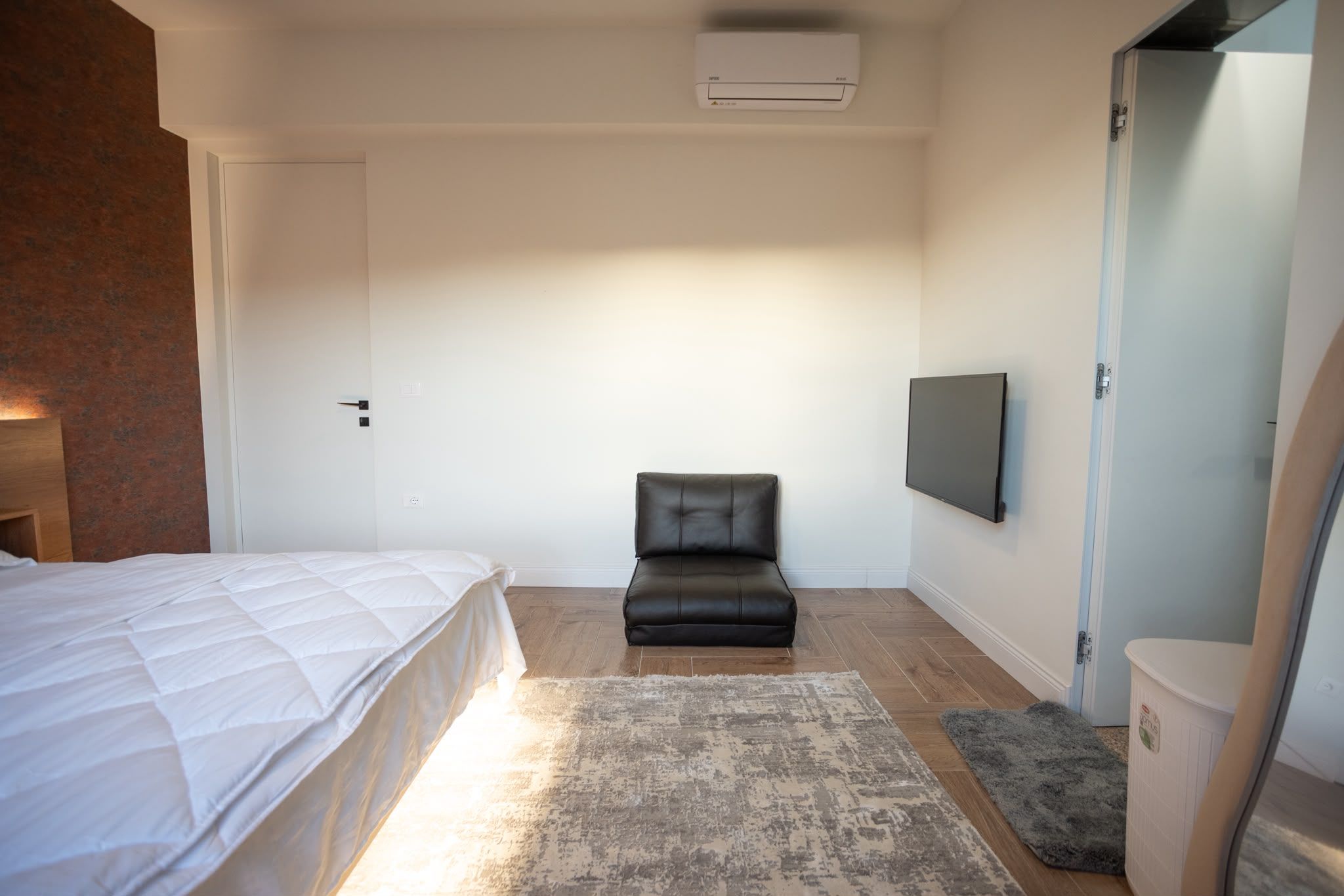 A bedroom with a bed, a chair, a television, and a wardrobe.