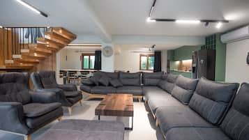 Una sala moderna con un sofá modular, sillones de cuero y una mesa de centro de madera.