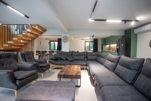 A modern living room with a sectional sofa, leather armchairs, and a wooden coffee table.