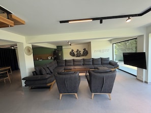 A modern living room with a sectional sofa, a flat-screen TV, and a wall-mounted artwork.