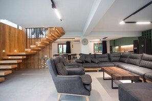 Una sala moderna con un sofá modular, una mesa de centro y una escalera con escalones de madera.