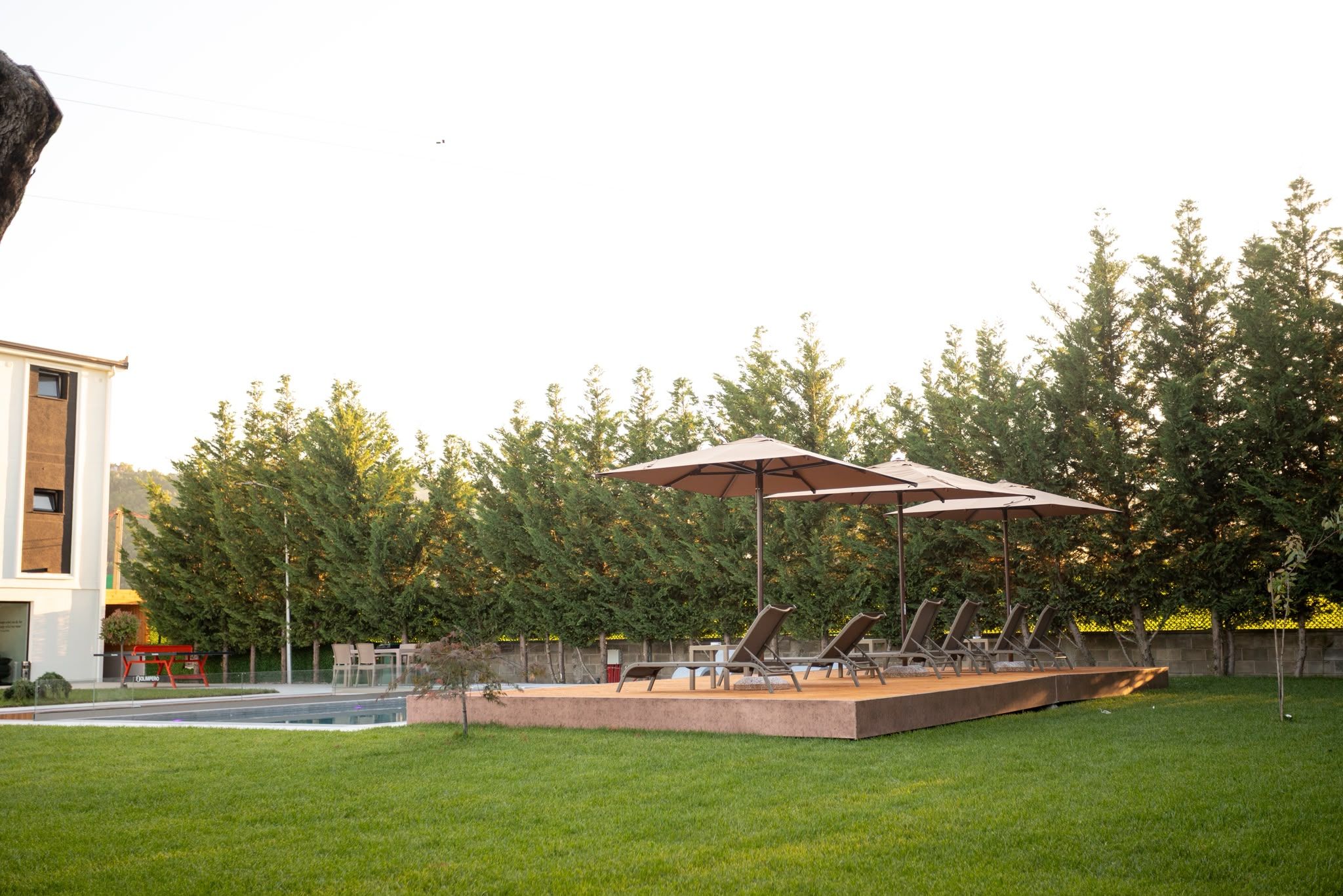 Ein Garten mit Schwimmbecken, Sitzgelegenheit im Freien und einem großen Sonnenschirm.