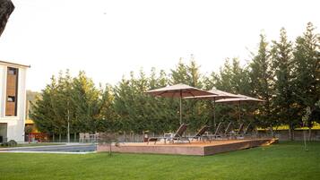Ein Garten mit Schwimmbecken, Sitzgelegenheit im Freien und einem großen Sonnenschirm.