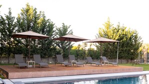 A swimming pool with lounge chairs and umbrellas, surrounded by trees.