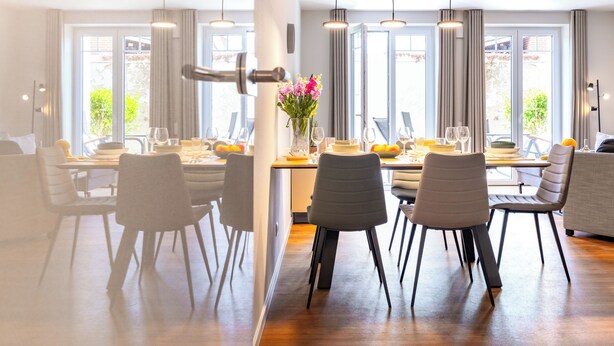 A modern dining area with a long table, multiple chairs, and pendant lighting. - Grömitz MeerNah No 4. sauna. Terrace. Close to the beach. (Grömitz)