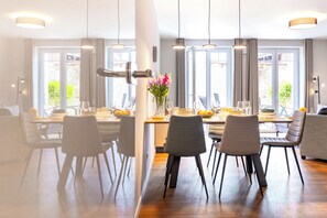 Een moderne eetruimte met een lange tafel, meerdere stoelen en hanglampen.