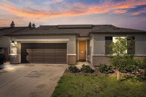 Une maison à deux étages avec un garage, une porte d’entrée et un petit jardin.