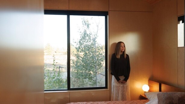 Una habitación con cama, ventana y lámpara de noche.