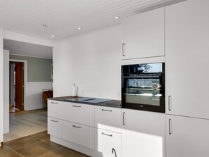 A modern kitchen with white cabinetry, a black countertop, and a built-in oven.