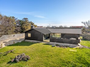 A modern house with a large open patio, a separate dining area, and a well-maintained lawn.