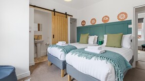 Habitación de hotel con dos camas, una puerta de madera, un baño y placas decorativas en la pared.