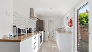 Una cocina moderna con armarios blancos, encimera de madera y vistas a través de un ventanal.