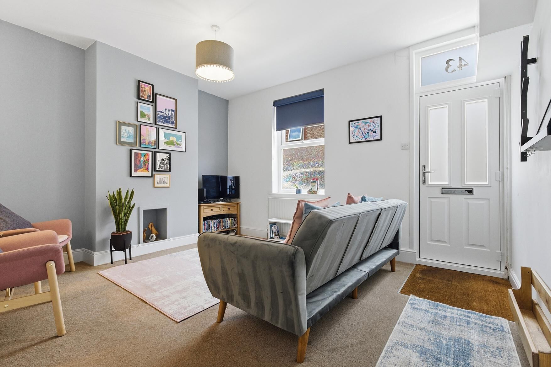 A living room with a sofa, a television, a bookshelf, and framed pictures on the wall.